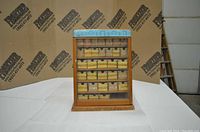 Front view of the wood hardware cabinet showing glass door and visible cardboard boxes