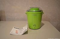 Overview photo showing assembled green Cuisinart ice cream maker next to instruction manual on table