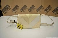 Front-side view of the cream-coloured leather purse with "Fiona" tag, showing quilted patchwork flap and adjustable strap.