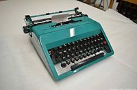 Front three-quarter view of turquoise Olivetti Studio 45 typewriter on white background