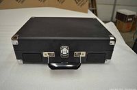 Front view of black Crosley portable record player suitcase closed with metal corner protectors and latch.
