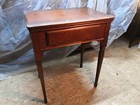 Closed sewing desk showing varnished wood surface and legs