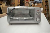 Front view of Black+Decker toaster oven showing door with wire rack and crumb tray inside
