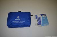 Blue Deuter transport cover folded in its pouch with logo and size printed