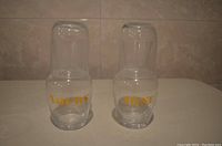 Front view of two clear glass carafes stacked with matching glasses serving as lids, showing gold lettering "Yours" and "Mine."