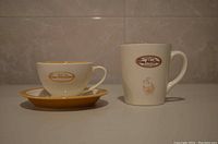 Side view of both Tim Hortons cups, showing the teacup with saucer and the limited edition #007 mug