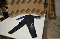 Full view of the black and blue Neosport wetsuit laid flat showing its design and condition.