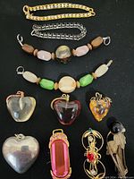 Photo showing two bracelets, two beaded necklaces, and three heart-shaped pendants laid out against a black background.