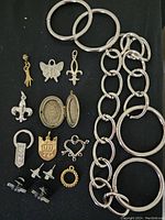 Jewelry lot showing silver bangles, large silver chain links, various pendants including butterfly, fleur-de-lis, heart, and more.