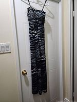 Full view of the long black and gray animal print dress hanging, showing overall length and silhouette.