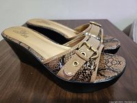 Side and top view of new wedge sandals showing snakeskin patterned straps with gold buckle and beige footbed.