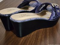 Side view of purple snakeskin platform sandals with black wedge heel and gold buckles, showing heel height and strap details.