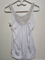 White women's sleeveless top hanging on a white hanger, showing full front view.