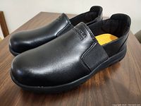 Side angle view of the black Dakota Workpro slip-on shoes showing smooth leather upper and elastic side panel.