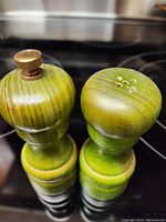 Top view showing pepper grinder wooden knob and salt shaker holes on top surface in green wood finish.