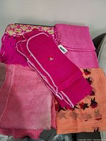 Lot of five large scarves arranged together on a couch showing variety of colors and patterns