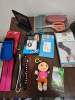 Various mixed personal items displayed on table including pantyhose pack, hair bands, phone covers, small plush toy, scissors, mirror, necklace, glasses case