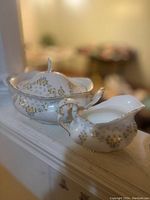 Photo showing a Victorian style porcelain serving dish set with a lidded tureen and creamer, decorated with floral patterns and gold trim.