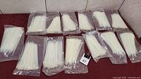 Thirteen packages of sealed white zip ties, each package containing approximately 100 zip ties.