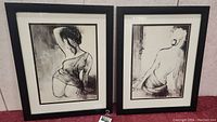 Two framed art pieces under glass showing black and white female silhouettes side by side.