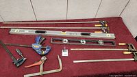 Photo of the lot showing two long bar clamps with wooden handles, one Stanley Xtreme aluminum level, a Stanley black torpedo level, an Irwin quick grip clamp, and two other clamps.