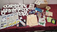 Full view of lot showing styrofoam letters, stencil sheets, paintbrushes, embroidery flyers, floral stickers, craft papers and tools