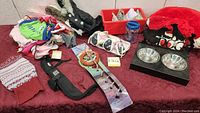 Overview of all items in the lot displayed on red cloth, multiple coats, collars, leashes, dishes and accessories