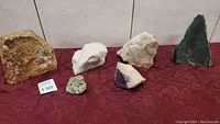 Photo showing full lot of six assorted rocks and minerals on red cloth.