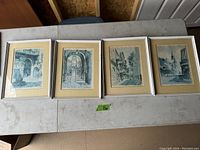 Four framed art prints by Don Davey with New Orleans scenes, laid on table.