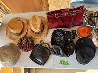 Photo showing four hats including wide-brim straw, straw with band, tweed flat cap, and black wool beret, plus several bags: a large maroon handbag, black backpack purse, velvet pouch, and orange pouch.