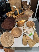 Overview of various woven baskets and hand brooms on display table