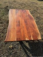 Photo showing the entire wooden coffee table top with live edge sides, highlighting the wood grain and color variations under daylight.