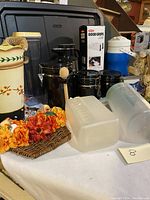 Overview of the black ceramic canisters, storage containers, faux flower tray, and a large black storage bin in the background.