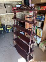 Full side view of the cherry wood six-tier display stand showing the turned spindles and carved top crest.