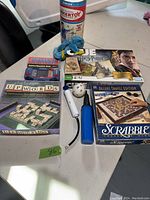 Lot showing Classic Tinkertoy set, various board games including Harry Potter Clue, Upwords, Deluxe Travel Edition Scrabble, electronic game wand and ball, and plush toy