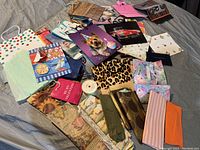Overview of gift bags collection showing various sizes and colorful designs spread out on gray fabric.