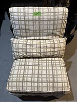 Slipcovered accent chair with beige and white plaid pattern, showing seat, back, and matching lumbar pillow.