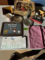 Overview of the assorted house items including welcome signs, mug, fruit decorations, ladle, cloth, plate, and planter