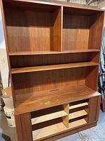 Full view of the upper shelving and lower cabinet showing wood grain finish, shelving compartments, and sliding doors.