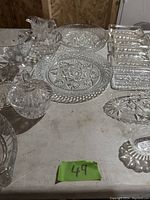 Top down view of multiple pressed glass items including plates, bowls, and trays arranged on a table