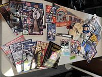 Top-down image showing full Patriots memorabilia collection on table including magazines, pennants, hats, and figurine.