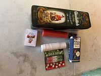 Poker set items including Glenfiddich tin box, poker chips, dice, and playing cards arranged on a surface.