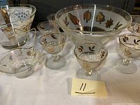 Front view of punch bowl set including punch bowl, glasses, and decanters with gold leaf detail