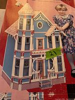 Photo of the front of the box showing the assembled model house and child model for scale.