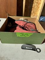 Box with one Timberland boot and Bally branded shoehorn beside it.