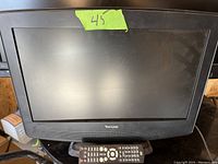 Front view of black Venturer LCD TV with screen off, remote control visible in front