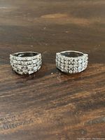 Photo showing two sterling silver rings with clear stones, placed on a wooden surface