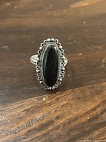 Front view of elongated black onyx set in detailed sterling silver ring.