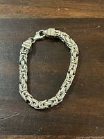 Full view of the silver bracelet laid flat on wood surface.