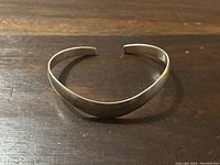 Photo showing the silver cuff bracelet from the front, displaying the curved shape and overall design.